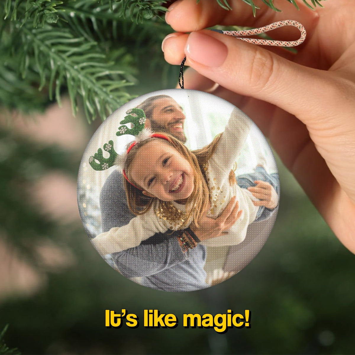 Video Memory Christmas Tree Ornament displaying a joyful family moment, held by hand with festive greenery in the background
